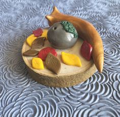 a small wooden object with different shapes and colors on it's surface, sitting on a blue patterned tablecloth