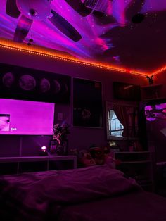 a bedroom with purple lighting and pictures on the wall