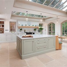 a large kitchen with an island and skylight in the center, surrounded by windows