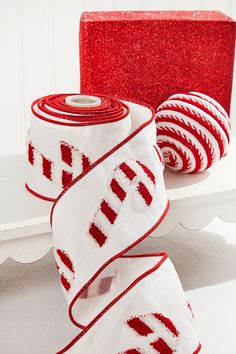 two rolls of red and white ribbon sitting on top of a table next to each other