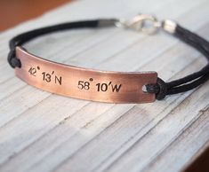 a leather bracelet with the date and time engraved on it, sitting on a wooden surface