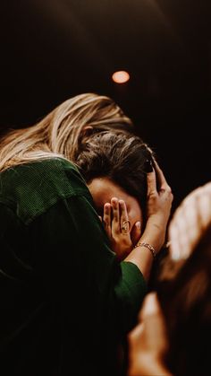 a woman is covering her face with her hands while sitting in front of a crowd