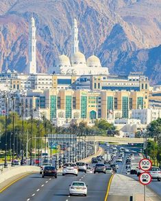 cars driving down the road in front of a large building with two towers on top