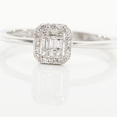 a white gold ring with an emerald cut diamond surrounded by small round brilliant pave diamonds