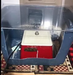 a red and white ice chest sitting on top of a checkered tablecloth covered floor