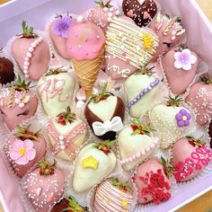 a pink box filled with lots of different types of decorated strawberries and chocolates