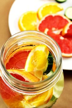 a jar filled with liquid next to sliced oranges and cucumbers