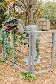 a fake dinosaur in a metal fence with ivy growing on it's back end