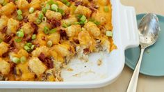 a casserole dish with tater tots, green onions and cheese on top