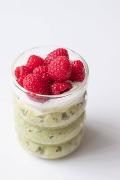 some raspberries are in a small glass bowl on top of other food items