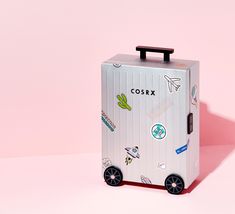 a white suitcase with stickers on it sitting in front of a pink background,