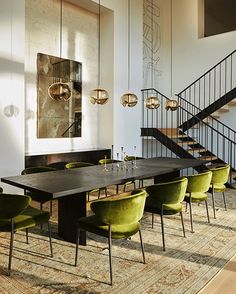 an elegant dining room with green chairs and a table in front of a staircase that leads up to the second floor