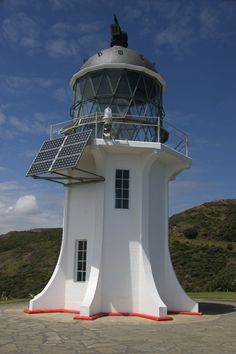 a white lighthouse with a solar panel on top