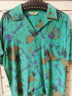 Original hawaiian shirt from the late 40s-50s in excellent condition. Blue green + purple + black + orangle colors. Loop collar. Wooden bamboo buttons. Aloha label. Marked a size M. Shoulder 18 3/4" Armpits 40" Waist 42" Length 8 1/2" Sleeve 25 3/4" Vintage Green Camp Shirt For Beach, Vintage Green Camp Shirt For The Beach, Vintage Green Hawaiian Shirt For Summer, Hawaiian Shirt With Vintage Print And Camp Collar, Vintage Blue Hawaiian Shirt With Tropical Print, Vintage Hawaiian Shirt With Short Sleeves For Vacation, Blue Vintage Hawaiian Shirt With Tropical Print, Retro Green Hawaiian Shirt For Vacation, Vintage Tropical Print Camp Shirt