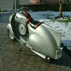 a silver motorcycle parked on top of a sidewalk