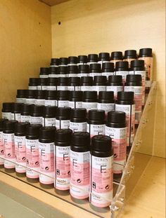 a shelf filled with lots of black and pink bottles