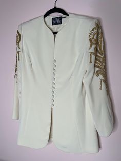 You can't go wrong with Bob Mackie. This "Evening" collection blazer is 90s perfection with sparkling beaded design work down both sleeves, structural shoulder pads, and buttons down the front. No flaws. Yes, it is a blazer/jacket but I would go ahead and wear this as a mini dress! 20" flat across the bust 18" flat at the waist 30" total length Labeled a Size 14 Please ask any questions prior to purchase. Thank you! Fitted Embellished Blazer For Festive Occasions, Embroidered Long Sleeve Evening Blazer, Long Sleeve Embroidered Evening Blazer, Festive Embellished Evening Blazer, Festive Evening Embellished Blazer, Embellished Fitted Blazer With Long Sleeves, Fitted Embellished Long Sleeve Blazer, Cream Blazer, Gold Embellishment