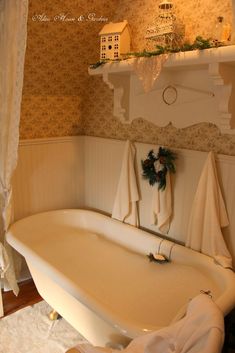 a white bath tub sitting under a window next to a shelf filled with candles and flowers