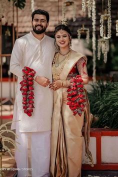 a man and woman standing next to each other in front of a flower arrangement on the ground