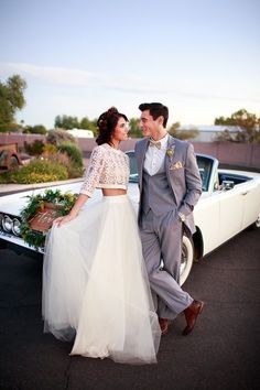 a man and woman standing next to each other in front of a white vintage car