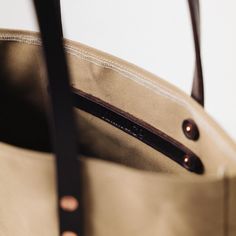 The Field Tan Canvas tote is a canvas and leather tote handmade in the KMM & Co. studio in Atlanta. Each one is meticulously crafted from heavyweight canvas and gorgeous full-grain leather. Field Tan Canvas is a type of cotton canvas known as duck cloth. It's one of the most durable types of cloth, and it's structured enough to stand up on its own. The Field Tan Canvas tote comes standard with Dark Brown handles. Waxed Canvas Bag With Leather Handles For On-the-go, Everyday Duck Canvas Bag, Canvas Tote Bag With Leather Lining, Leather Canvas Bag With Canvas Lining For On-the-go, Classic Everyday Waxed Canvas Bag, Canvas Satchel Bag With Leather Lining, Everyday Use Canvas Shoulder Bag With Leather Lining, Everyday Canvas Shoulder Bag With Leather Lining, Classic Canvas Shoulder Bag With Leather Lining