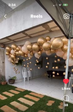 an outdoor area with lots of balloons hanging from the ceiling and grass in front of it