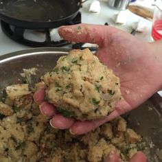 a person holding food in their hand over a pan on the stove top with other cooking utensils nearby