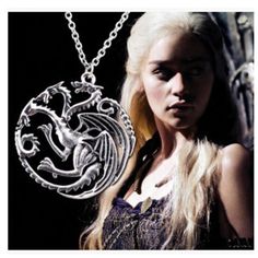 a woman with long blonde hair wearing a silver necklace and holding a dragon on it's back