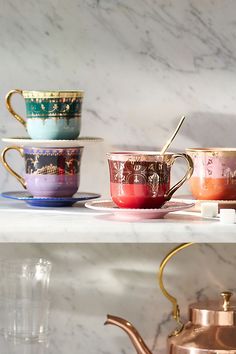 tea cups and saucers are lined up on the shelf in front of a marble wall