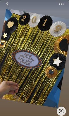 a person is holding up a sign in front of some gold and black decorations that say happy new year