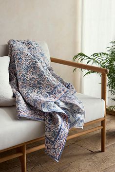 a couch with a blanket on it next to a potted plant