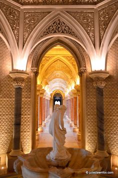 a statue is in the middle of an ornate hallway with columns and arches on both sides