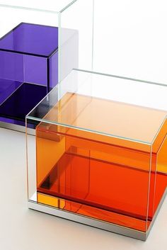 three different colored boxes sitting next to each other on a white surface with no one in it