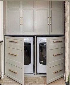 a washer and dryer are in the middle of a kitchen with white cabinets