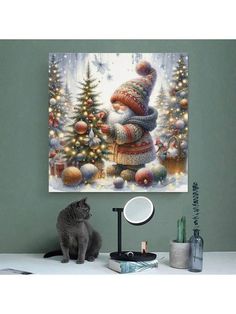 a cat sitting in front of a christmas painting on the wall next to a mirror