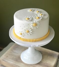 a white and yellow cake with daisies on it