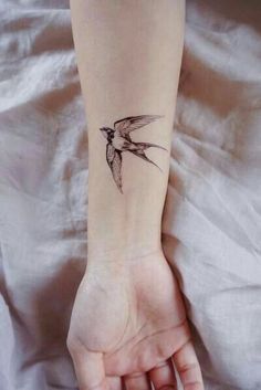 a small hummingbird tattoo on the left inner arm and wrist is shown in black ink