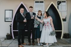 a group of people standing next to each other in front of a building holding wine glasses