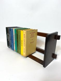 a wooden book holder with five books on it's sides and one in the middle