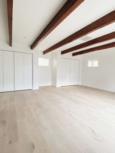 an empty room with white cabinets and wood floors