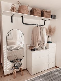 a bedroom with a mirror, dresser and clothes rack