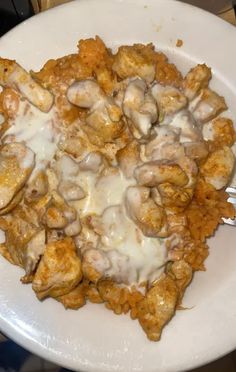 a white plate topped with meat covered in sauce and mushrooms next to a fork on top of a table