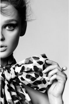 a woman with blue eyes wearing a leopard print bow around her neck is posing for the camera