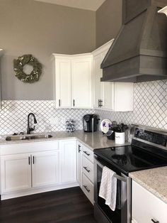 a kitchen with white cabinets, black stove top and stainless steel range hood over the sink