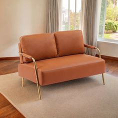 a tan couch sitting on top of a wooden floor in front of a large window