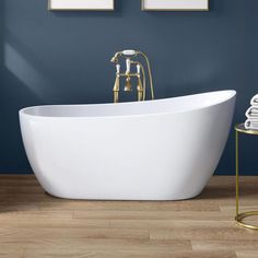 a white bath tub sitting on top of a wooden floor next to a blue wall