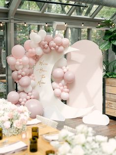 the balloon arch is decorated with pink and white balloons