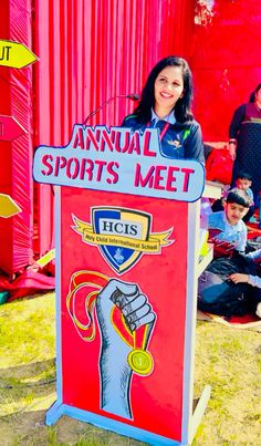 a woman standing behind a sign that says annual sports meet in front of other people