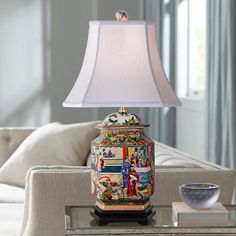 a table lamp sitting on top of a glass table next to a white couch in a living room