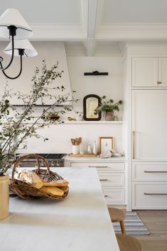 an image of a kitchen with white cabinets and counter tops in the background, there is a basket on the island